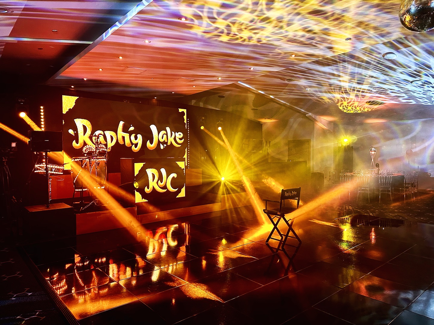 Raphy’s personalised stage and reflective dance floor under golden lighting at the Amber Suite